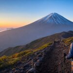 A climber on a Mt. Fuji trail at sunrise, representing mountain hut reservation planning