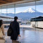 Travelers transferring by train and bus toward Lake Kawaguchiko with Mt. Fuji beyond