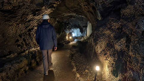 A traveler wearing a jacket and helmet inside a Mount Fuji lava cave