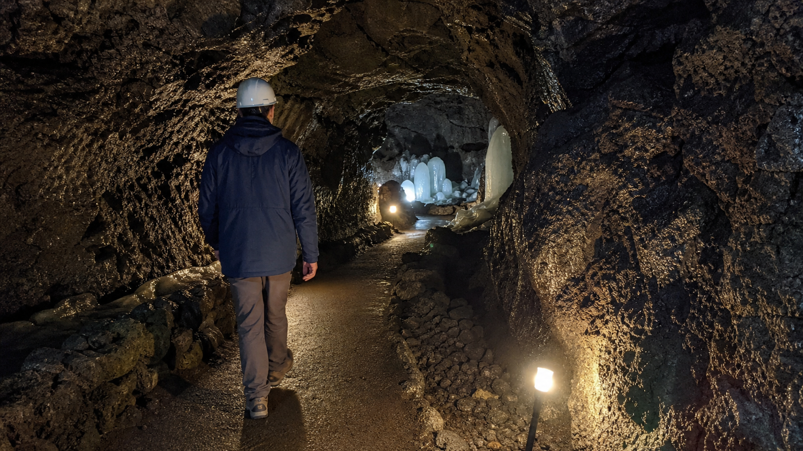 A traveler wearing a jacket and helmet inside a Mount Fuji lava cave