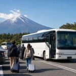 Travelers walking from a parking area toward a shuttle bus with Mt. Fuji in the background