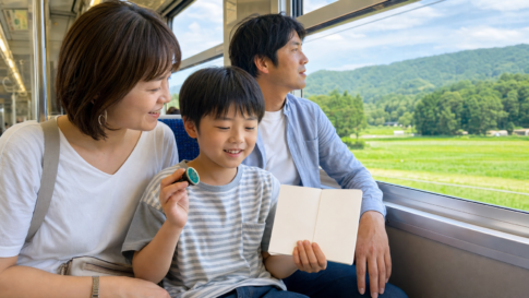 A child holding a blank stamp booklet while riding a local train with family