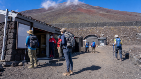 Prepared hikers checking a mountain support station on Mt. Fuji for a 2026 first-aid facilities update