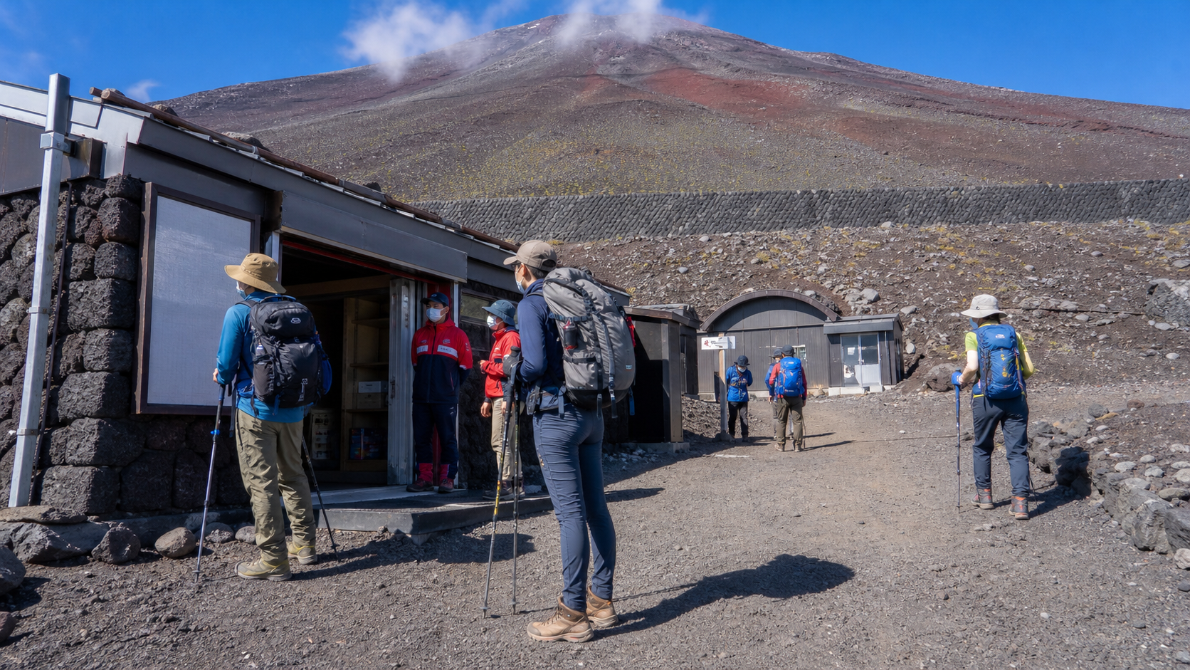 Prepared hikers checking a mountain support station on Mt. Fuji for a 2026 first-aid facilities update