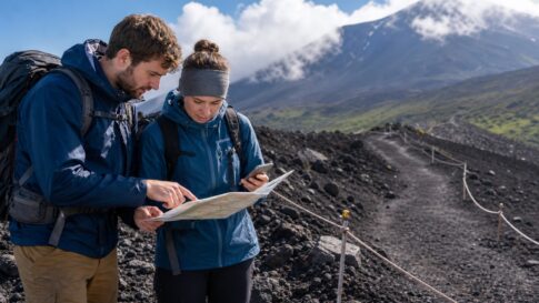 Travelers checking a map on a volcanic Mt. Fuji trail in summer weather