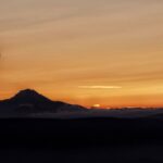 A hot-air balloon beside a mountain at sunrise