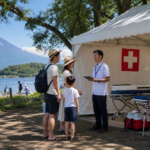 Family speaking with staff at a lakeside first-aid station in Yamanakako for a summer visitor update