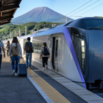 Text-free white limited-express train at a Japanese platform with travelers and snow-free Mount Fuji