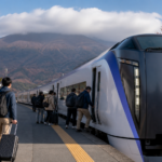 Text-free white limited-express train boarding at an autumn platform near cloud-covered Mount Fuji