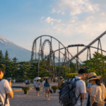 Travelers planning a summer amusement park visit beside a roller coaster and Mount Fuji