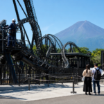 Text-free view of a roller coaster inspection at a Fuji foothills amusement park with bare Mount Fuji beyond