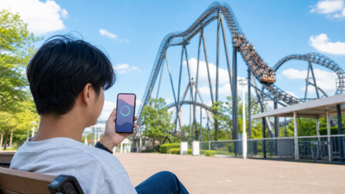 A visitor checking an unlabeled progress ring on a smartphone beside a roller coaster