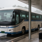 Travelers checking bus information under a covered terminal while heavy rain falls