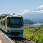Travelers waiting for an unbranded local train with Mount Fuji and a lake in the background