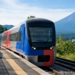 Plain blue and red local train at a rural Mount Fuji foothills station on a clear summer morning