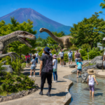 Families viewing robot dinosaurs and a shallow water area near Mount Fuji