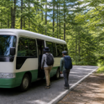 Two hikers boarding a small seasonal bus on a forest road toward Umagaeshi