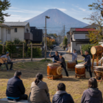 Small text-free neighborhood taiko and acoustic guitar performance in Fujiyoshida with bare Mount Fuji beyond
