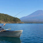 Angler in a plain life jacket fishing from a small boat on Lake Motosu with bare Mount Fuji beyond