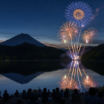 Fireworks reflected across forest-ringed Lake Saiko at night
