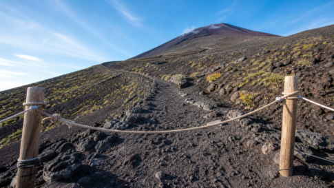 A rope barrier across an empty volcanic hiking trail on snow-free Mount Fuji