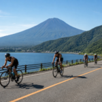 Road cyclists on a closed lakeside road with event marshals and snow-free Mount Fuji in the distance