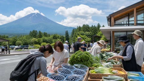Travelers browsing blueberries and highland vegetables at a roadside station below Mount Fuji