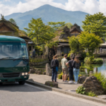 A plain green local bus beside clear spring ponds and traditional wooden buildings in a summer village