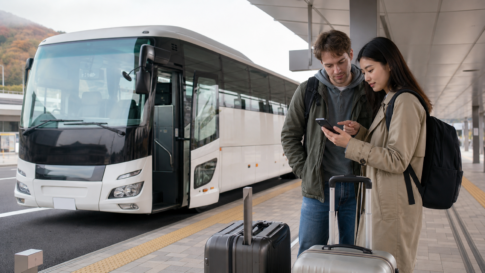 Text-free highway coach at a Japanese bus terminal with two travelers checking a smartphone reservation