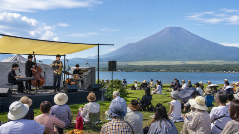 Text-free outdoor jazz ensemble performing for a lakeside audience with snow-free Mount Fuji