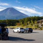 Text-free quiet Mount Fuji parking area with a few cars and travelers preparing walking gear