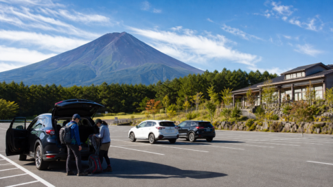 Text-free quiet Mount Fuji parking area with a few cars and travelers preparing walking gear