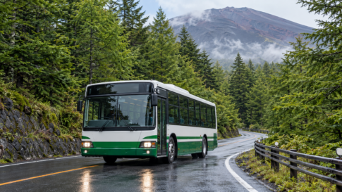 An unbranded local bus traveling on a wet forested road on Mount Fuji