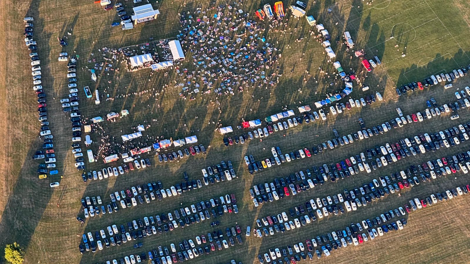 Aerial view of a busy outdoor concert area and its large temporary car park