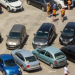 A busy event parking area filled with cars and visitors
