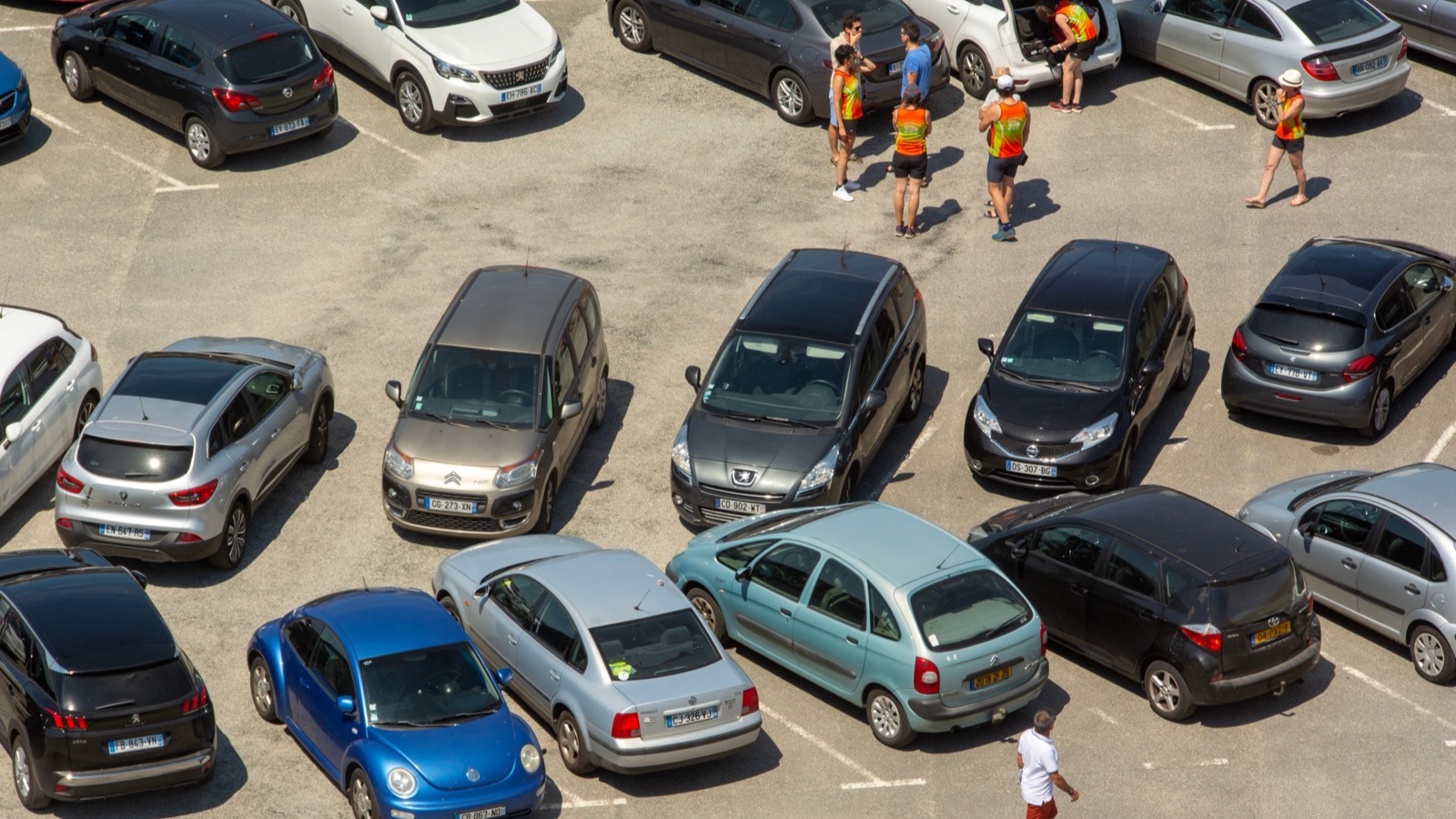 A busy event parking area filled with cars and visitors