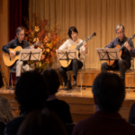 An acoustic guitar ensemble performing in a small community hall
