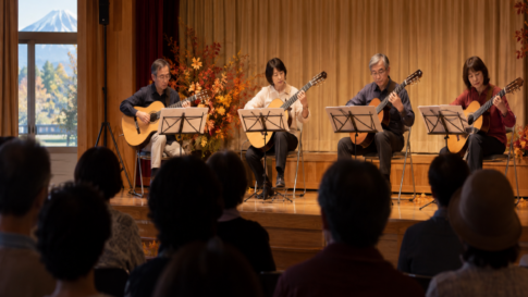 An acoustic guitar ensemble performing in a small community hall