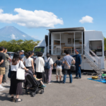 Text-free disaster preparedness event with families, an emergency demonstration vehicle, and Mount Fuji