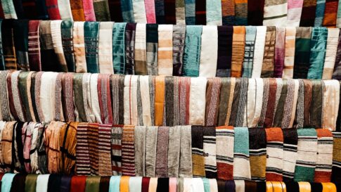 Rows of colorful woven textiles displayed at a market stall