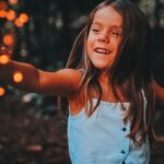 A child safely enjoying a handheld sparkler outdoors at dusk