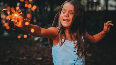 A child safely enjoying a handheld sparkler outdoors at dusk
