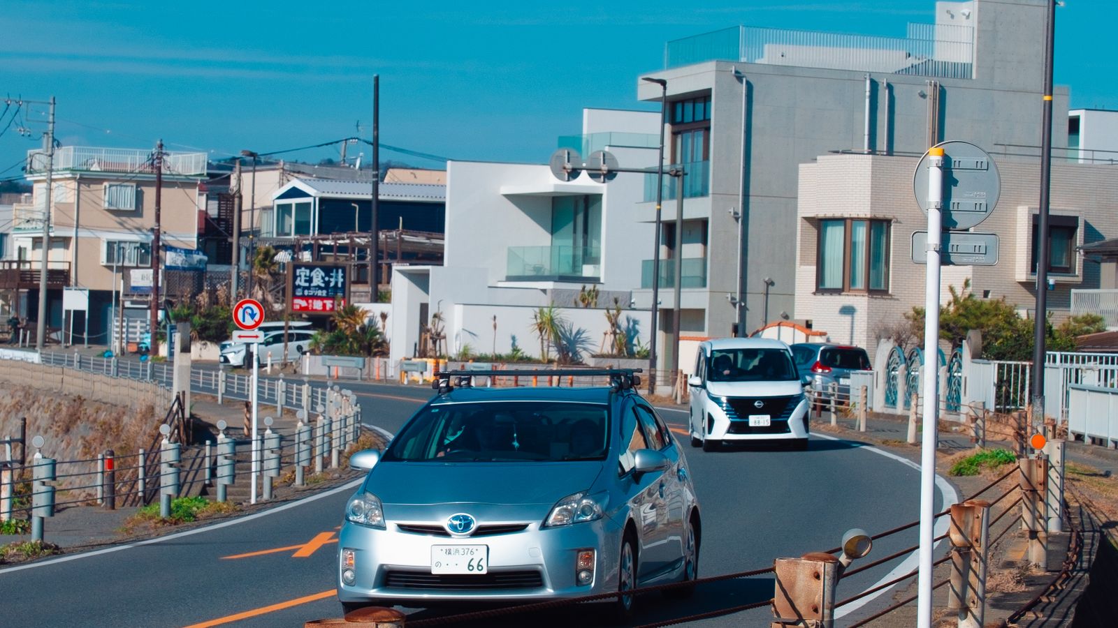 Cars driving carefully on a narrow residential road in Japan