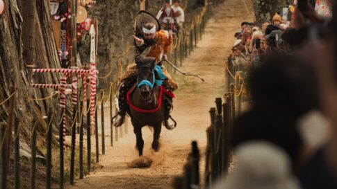 A traditional Japanese yabusame rider performing horseback archery in front of festival spectators