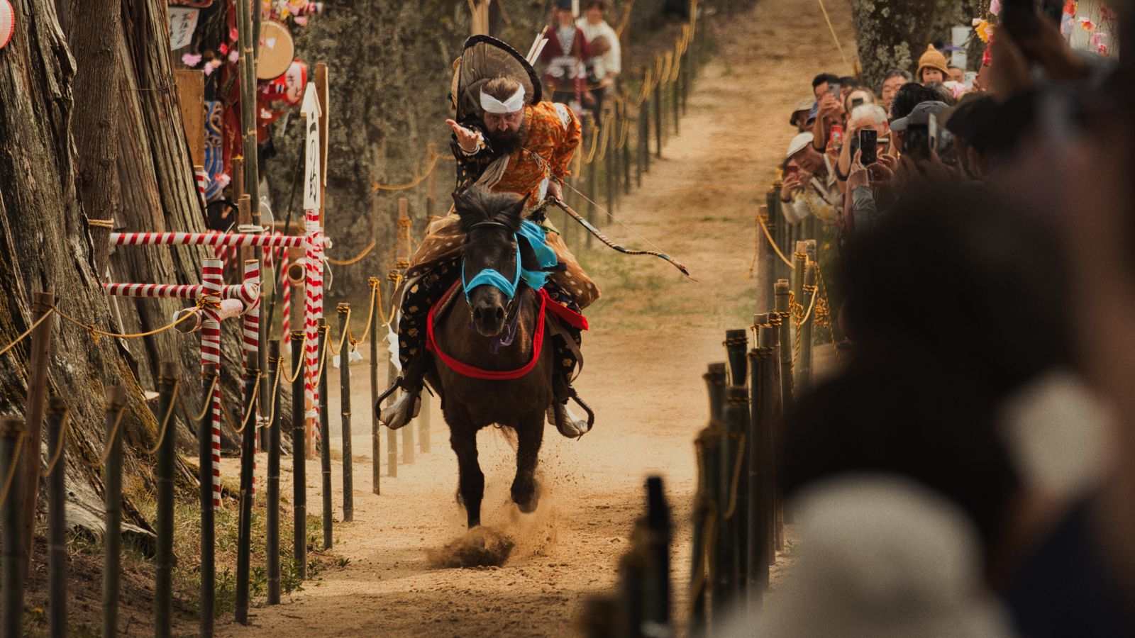 A traditional Japanese yabusame rider performing horseback archery in front of festival spectators