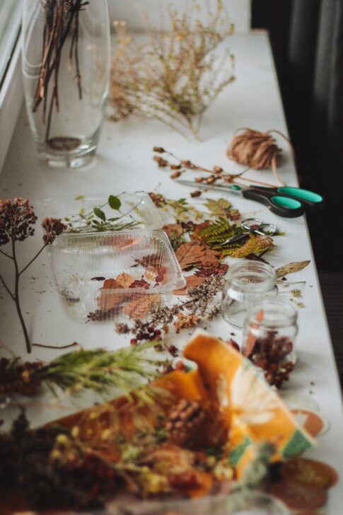 Dried flowers, twine, scissors and glass containers arranged for a botanical craft activity