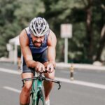 A triathlete cycling through a coned road section during a race