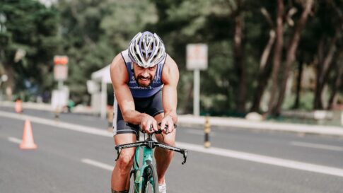 A triathlete cycling through a coned road section during a race