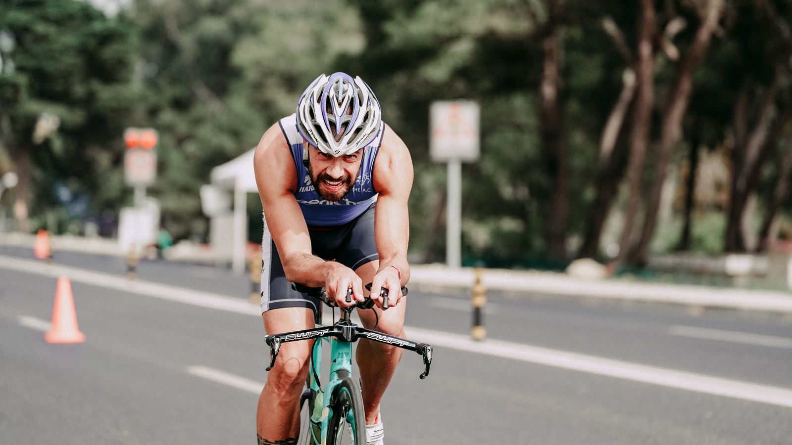 A triathlete cycling through a coned road section during a race