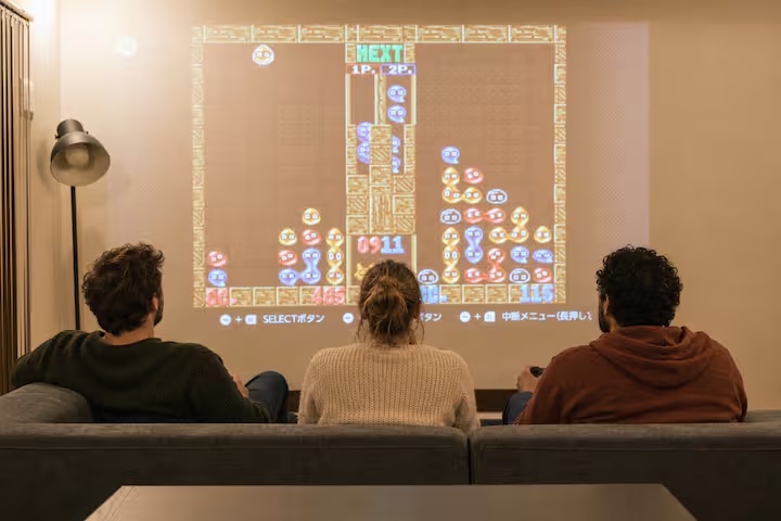 Three guests playing a projected video game in the living room at KINFOLK YAMANAKAKO